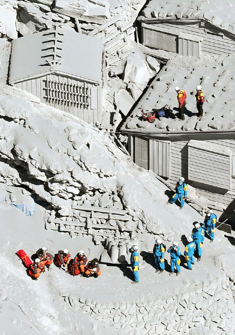 Firefighters and members of the Japan Self-Defense Forces prepare to rescue climbers near the peak of Mount Ontake in central Japan, Sunday, Sept. 28, 2014. Mount Ontake erupted shortly before noon Saturday, spewing large white plumes of gas and ash high into the sky and blanketing the surrounding area in ash. Rescue workers on Sunday found more than 30 people unconscious and believed to be dead near the peak of an erupting volcano, a Japanese police official said. (AP Photo/Kyodo News) JAPAN OUT, MANDATORY CREDIT