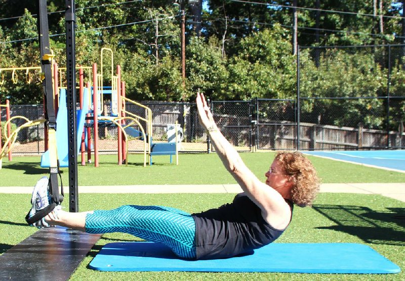 Arkansas Democrat-Gazette/CELIA STOREY
Personal trainer Beverly Lindberg does the second step of the TRX Situp exercise at Little Rock Racquet Club.