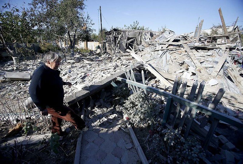 A woman observes damage at a destroyed home after shelling in the town of Donetsk, eastern Ukraine, Monday, Sept. 29, 2014. Eastern Ukraine has suffered the worst violence in more than a week as fighting between pro-Russian rebels and government troops in the region killed at least 12 people and wounded many, officials said Monday. (AP Photo/Darko Vojinovic)