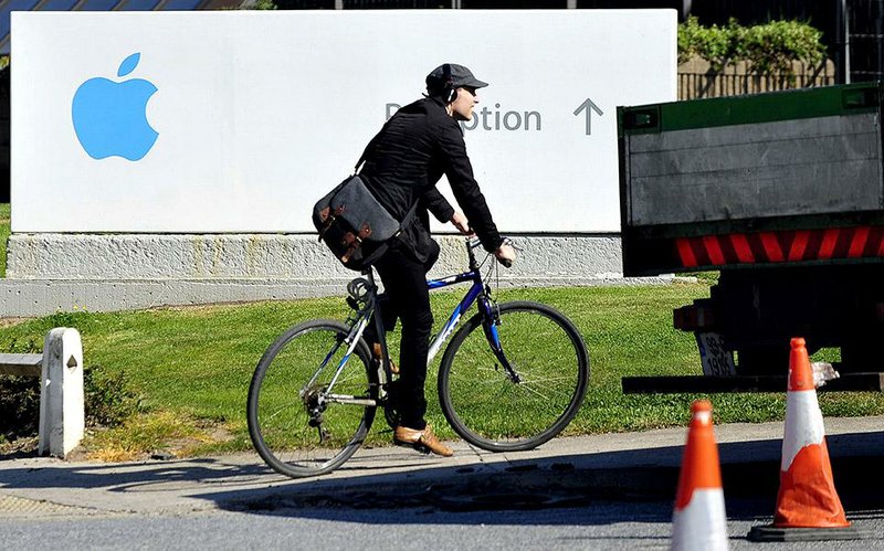 A cyclist passes a sign marking Apple Inc.’s campus in Cork in this 2013 file photo. Apple appears to be benefiting from improper tax deals, the European Union’s competition watchdog said Tuesday.