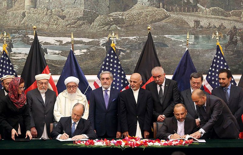 U.S. Ambassador James Cunningham (seated, left) and Afghan national security adviser Hanif Atmar (seated, right) sign the security agreement Tuesday at the presidential palace in Kabul as new leader Ashraf Ghani Ahmadzai (fourth from right, standing) and other officials observe.