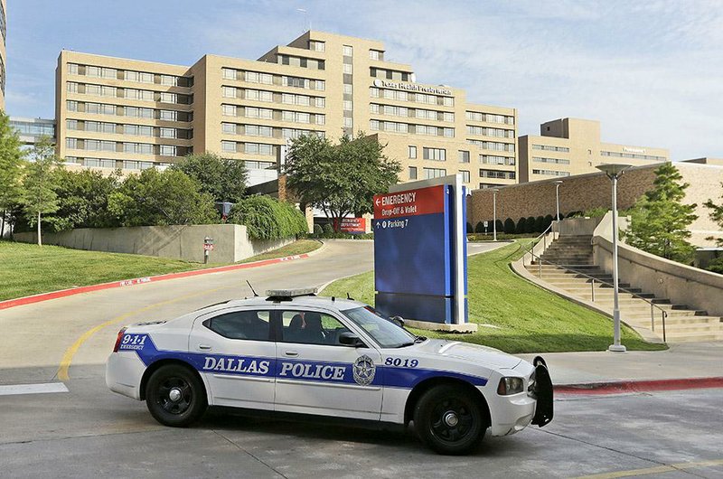 A police car drives past the entrance to the Texas Health Presbyterian Hospital on Tuesday in Dallas, where a patient has tested positive for Ebola.