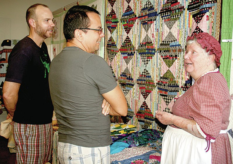 PAT HARRIS ENTERPRISE-LEADER Luis Murillo and John Lehnen of Fort Smith listened to Lillian McConnell describe the stories behind many of the quilts displayed at the quilt show held in a lower room in the Cane Hill College. Murillo and Lehnen said they enjoyed hearing about the history of quilting. For related photos, see page 6A.