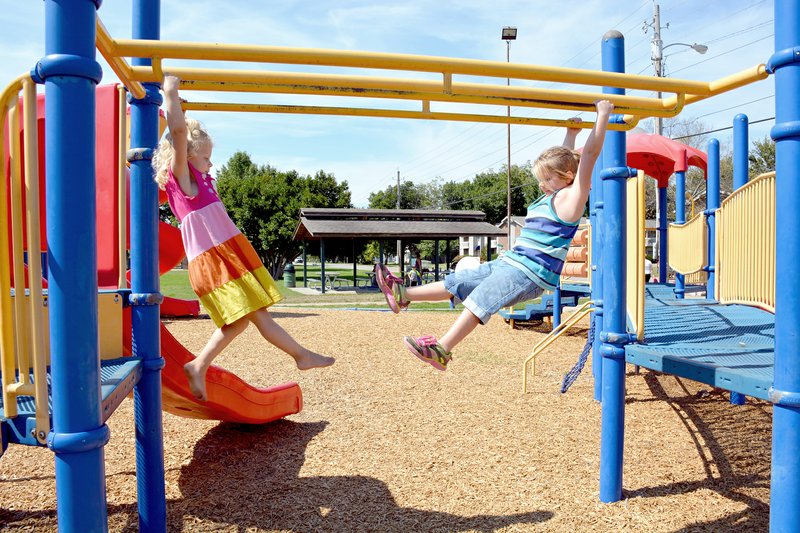 Tina Parker/Herald-Leader Julia Robinson, 4, and Amber Letlow, 5, both of Siloam Springs, swing on the monkey bars at Bob Henry Park. Their parents brought them to the park Thursday to play and enjoy the cooler weather.