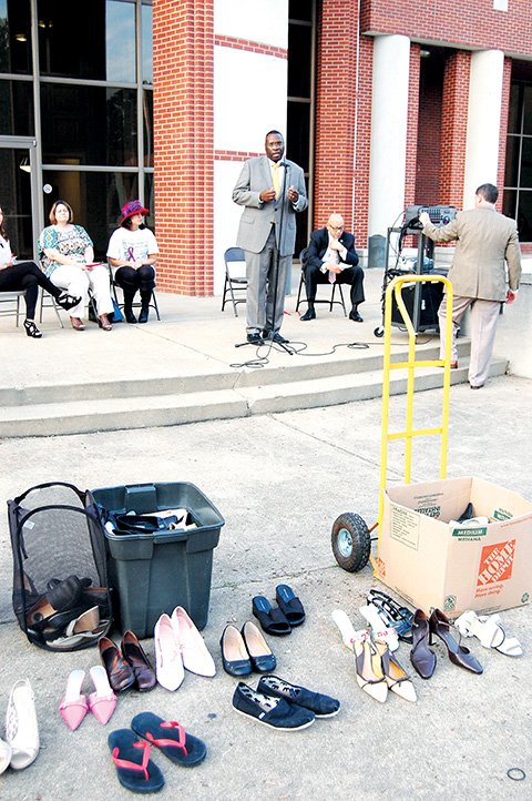 Women’s shoes, worn by men for a march through the Henderson State University campus, sit in front of HSU President Glen Jones while he addresses a gathering of students taking part in an effort to raise awareness of violence against women. About 100 students heard speakers talk about recognizing dangerous relationships, reporting attacks and being survivors who overcome abuse.