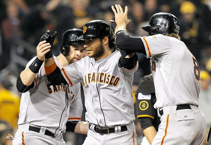 San Francisco shortstop Brandon Crawford (center) is greeted by teammates after a fourth-inning grand slam started the Giants on their way to an 8-0 victory over Pittsburgh in the National League wild-card game. It was the first grand slam by a shortstop in postseason history. Madison Bumgarner (below) handled the rest, striking out 10 and allowing only four hits in a complete game.