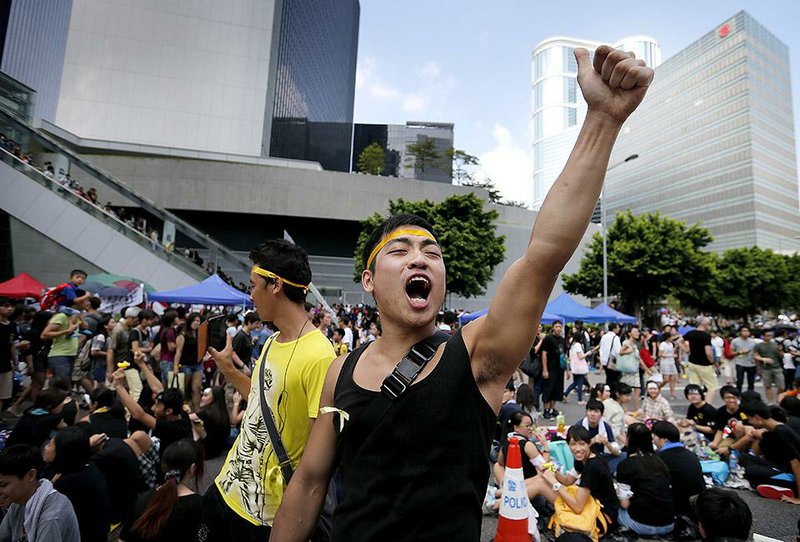 A pro-democracy activist joins a demonstration Wednesday outside government headquarters in Hong Kong, where protesters, demanding freer elections and the territory’s top official’s resignation, have been camped in the biggest challenge to Beijing’s authority since China took control of the former British colony in 1997. The Communist Party-run newspaper warned of “unimaginable consequences” if the protests don’t end.