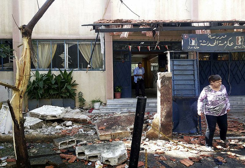 Syrians check the damaged school entrance Wednesday in Akrama neighborhood in the Syrian city of Homs. One explosion occurred as children were leaving the school, and a second blast came as parents were carrying bodies away.