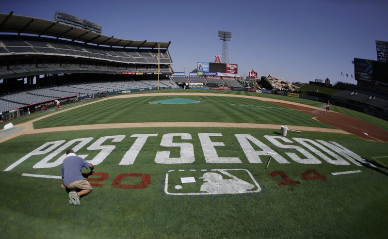 Bert McMenamim paints a postseason logo on the field before batting practice in Anaheim, Calif., Wednesday, Oct. 1, 2014. The Los Angeles Angels play Game 1 of the best-of-five AL division series against the Kansas City Royals on Thursday.