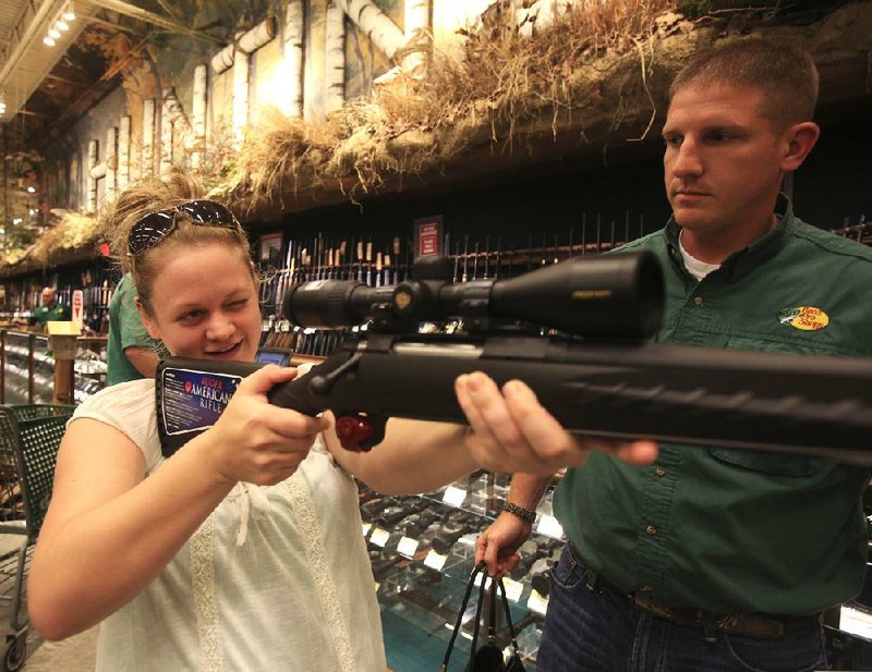 Tuesday Shelnutt (left) of Benton checks out the scope on her new Ruger .270 bolt-action ri•e with gun sales associate Eric Carpenter on Thursday at the Bass Pro Shops Outdoor World in Little Rock.