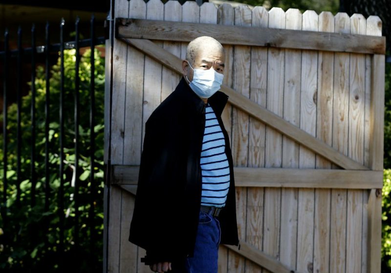 A neighbor takes precautions Saturday to carry out the trash at his home in Dallas across the street from the apartments where Ebola patient Thomas Eric Duncan stayed last month.