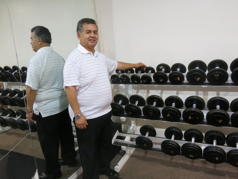 Photo by Susan Holland Frankie Valdez, new manager of the Gravette Gym, displays the wide variety of free weights which are available for use by gym members. The gym houses a number of other exercise machines including the bench press, leg press, Smith machine, ab machine, treadmill, stationary bikes and punching bags. Tanning beds are also available.