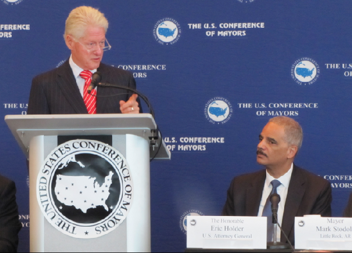 Former President Bill Clinton speaks while U.S. Attorney General Eric Holder looks on Wednesday during a policing forum in Little Rock.