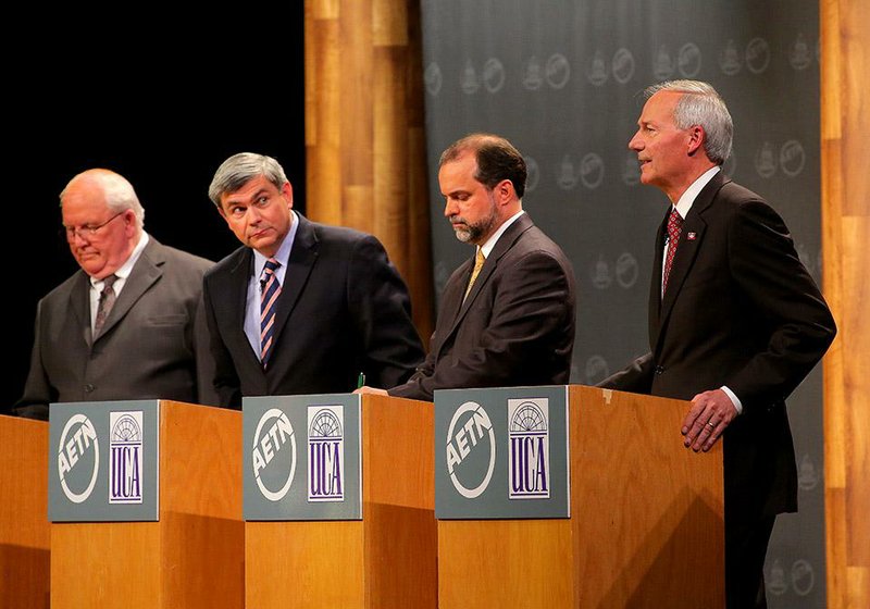 10/16/14
Arkansas Democrat-Gazette/STEPHEN B. THORNTON
Democratic gubernatorial candidate Mike Ross, second from left, leans over his podium to listen to a response concerning the private option from Republican candidate Asa Hutchinson as Green Party candidate J. Joshua Drake, center, looks over his notes  during the taping of Election 2014: AETN Debates at the Reynolds Performance Hall on the University of Central Arkansas campus Thursday in Conway, Ark. At left is Libertarian candidate Frank Gilbert .