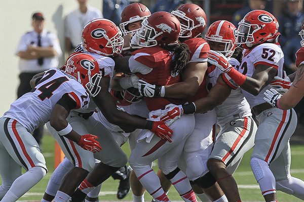 Arkansas running back Alex Collins is stuffed by Georgia defenders during a game Saturday, Oct. 18, 2014 at War Memorial Stadium in Little Rock. 