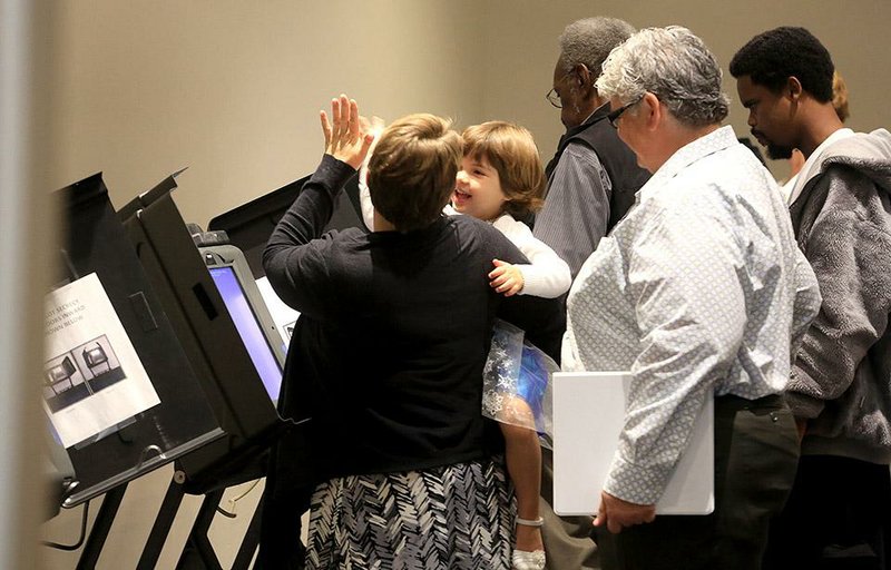 Arkansas Democrat-Gazette/RICK MCFARLAND  --10/20/14--  Barbara L'Eplattenier cq, high fives with her daughter Calliope, 3, of North Little Rock, after participating  Monday on the first day of early votingin Little Rock for the Nov. 4, general election.
