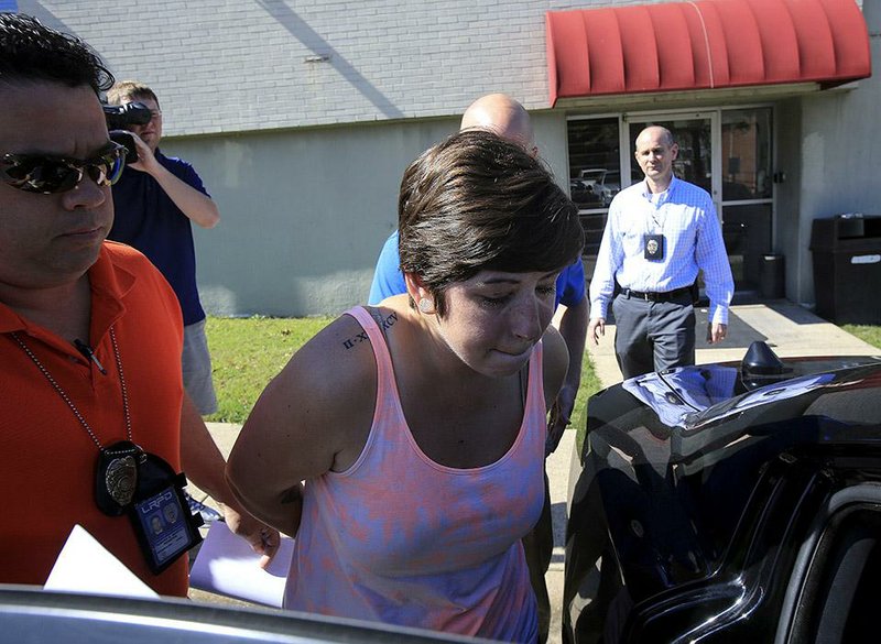 Little Rock detective Robert Martin escorts bank robbery suspect Katherine Clark, 26, to a waiting police car Monday afternoon. Clark, who was charged with aggravated robbery and theft of property, is suspected in the Monday robbery of the Arvest Bank branch at 11331 Arcade Drive.