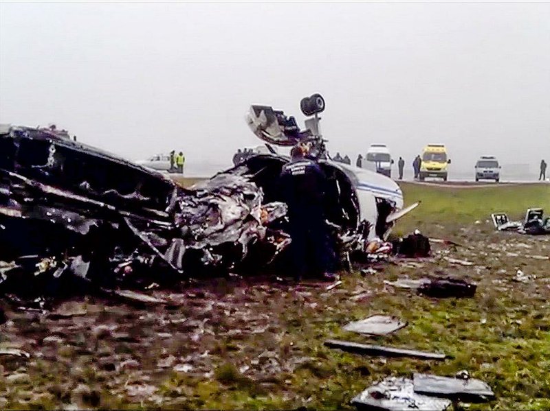 In an image made from video provided by Russian state television Rossiya, investigators work at the wreckage of a private jet that hit a snowplow Tuesday at Vnukovo airport in Moscow.