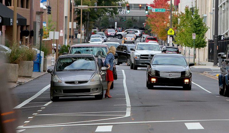 10/23/14
Arkansas Democrat-Gazette/STEPHEN B. THORNTON
A woman gets out of her car she just parked in the middle of Louisiana Street near Capitol Ave. during rush hour Thursday afternoon in downtown Little Rock. A new parking pattern allows vehicles to park in the middle of the street, while traffic, right of the woman, flows in one lane and a bike lane, left, of her car, separates traffic from the bikes.