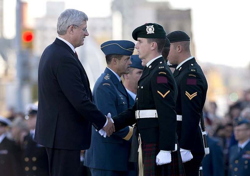 Canadian Prime Minister Stephen Harper, left, and General Tom Lawson, Chief of the Defence Staff of the Canadian Armed Forces, centre, take part in a ceremony to return ceremonial guards to the Tomb of the Unknown Soldier at the National War Memorial in Ottawa on Friday, Oct. 24, 2014. The sentries returned to their posts two days after Cpl. Nathan Cirillo, 24, a reservist from Hamilton, Ont., was killed by a gunman while guarding the tomb, who then moved to nearby Parliament Hill, opening fire before he himself was shot dead.  (AP Photo/The Canadian Press, Justin Tang)