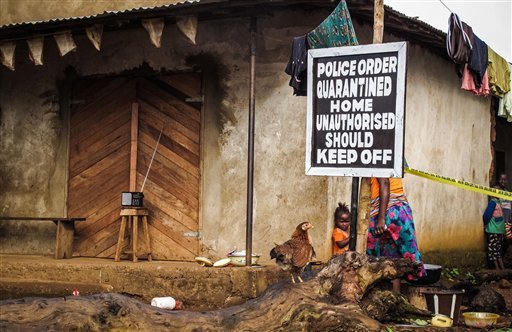 In this Wednesday, Oct. 22, 2014 file photo, a child stands near a sign advising of a quarantined home in an effort to combat the spread of the Ebola virus in Port Loko, Sierra Leone. More than 10,000 people have been infected with Ebola, according to figures released Saturday, Oct. 25, 2014 by the World Health Organization, as the outbreak continues to spread. Of those cases, 4,922 people have died. 