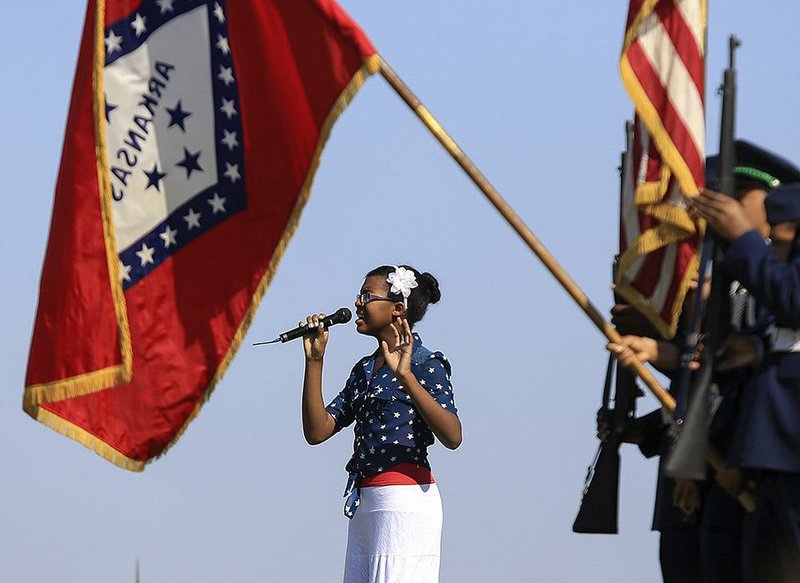 Kyndal Collins, 12, of Little Rock sings the National Anthem on Saturday at the Build Communities Not Bullies event as the Central High School Air Force Junior ROTC color guard presents the colors.
