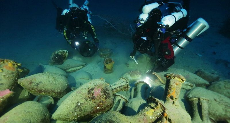 In this undated photograph provided by Global Underwater Explorers, divers illuminate Greco-Roman artifacts of a ship that sunk during the Punic Wars between 218-201 B.C., in the Mediterranean Sea, off the Aeolian Island of Panarea near Italy. The technical divers, trained in Florida's labyrinth of underwater caves, descended 410 feet to the wreck site to retrieve many of the ancient artifacts. (AP Photo/GUE, Ingemar Lundgren)