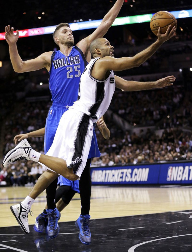 San Antonio guard Tony Parker (front) shoots around Dallas forward Chandler Parsons on Tuesday during the second half of the Spurs’ 101-100 victory over the Mavericks in San Antonio.