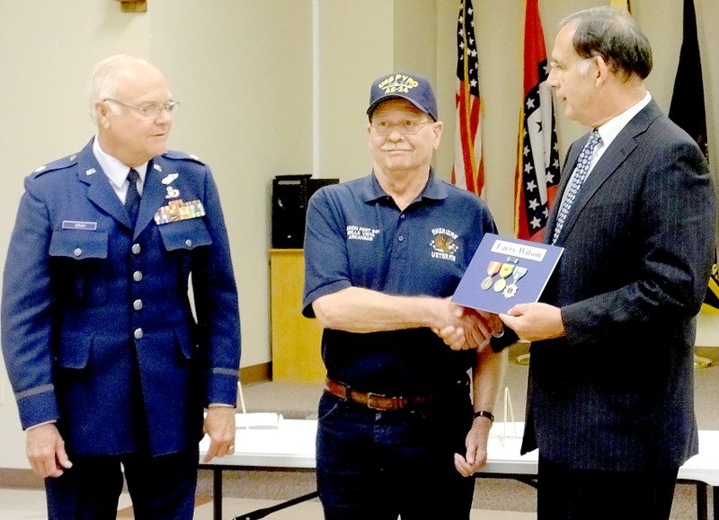 Lynn Atkins/ The Weekly Vista Larry Wilson of Bella Vista accepts his medals from Senator John Boozman at a ceremony at the American Legion Post on Friday while retired Lt. Col. Steven Grey looks on. Wilson, a Navy veteran, served as a maintenance engineer on a munitions ship during the Vietnam War.