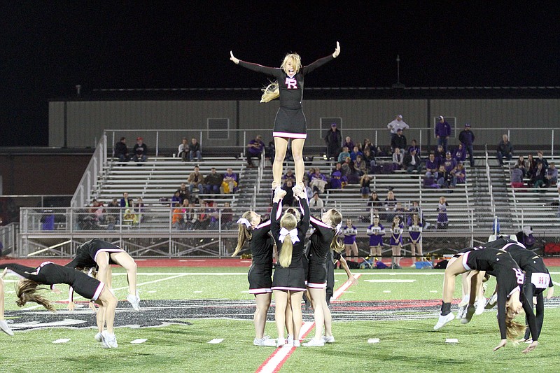 Varsity Blackhawk cheerleaders flip backwards as one rises above them all during a performance Friday night.