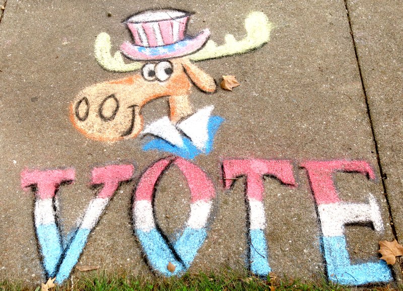 Photo by Mike Eckels In keeping with the 500-year-old tradition of sidewalk art, artist Mike Kelly uses Bullwinkle J. Moose to tell voters to get out and cast their ballots on Nov. 4. In the 16th century, sidewalk art was often used as social commentary to spread the word.