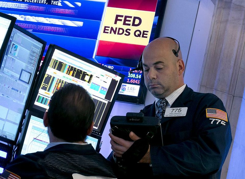 Trader Fred DeMarco works on the floor of the New York Stock Exchange on Wednesday as news of the Fed’s plans is displayed overhead.