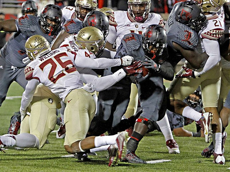 Louisville running back Michael Dyer (middle) runs through an arm tackle by Florida State defender DeMarcus Walker to score one of his three touchdowns in the No. 25 Cardinals’ 42-31 loss to the No. 2 Seminoles on Thursday in Louisville, Ky. Dyer, formerly of Little Rock Christian, ran for 134 yards on 28 carries.