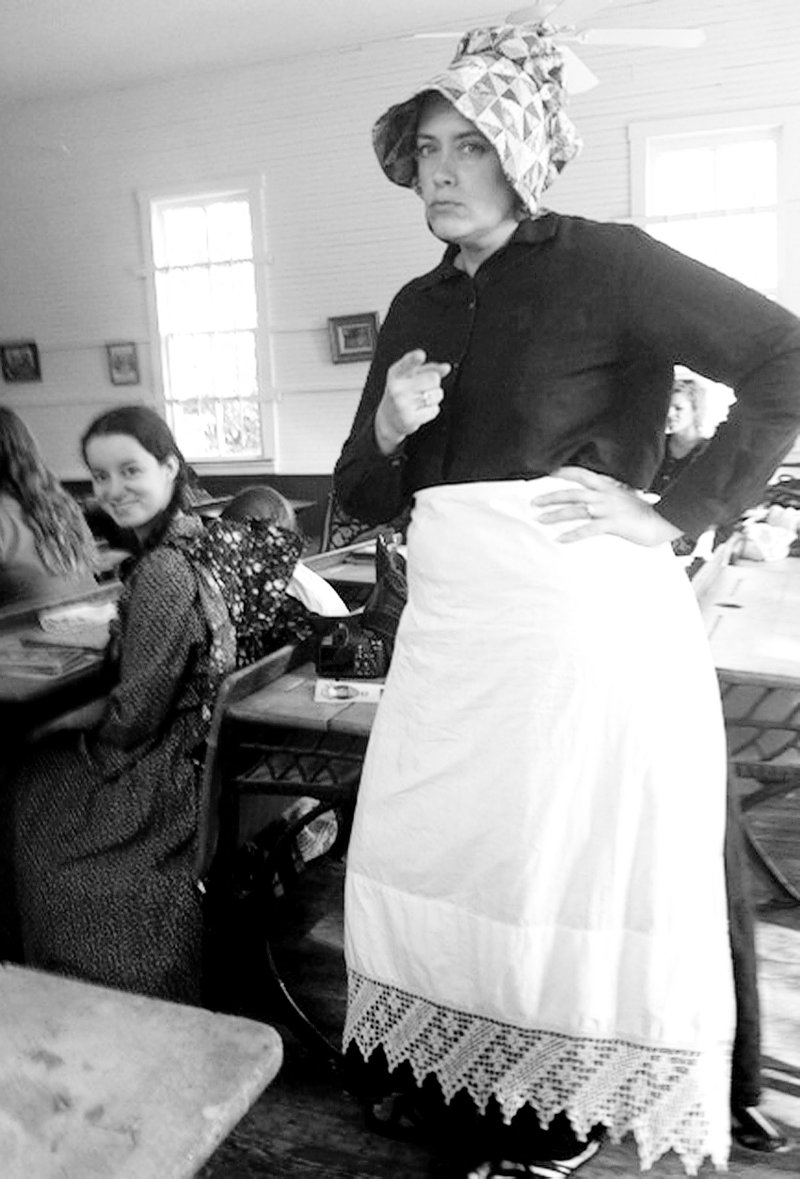 Photo by Allyson Ransom Sheila Martin of Gravette, who homeschools her four daughters, got in the spirit of the occasion and dressed in pioneer garb for the homeschool group&#8217;s trip to Rocky Branch School. Here she plays the role of the teacher and appears to be scolding an errant pupil. Both students and parents enjoyed learning about school days a century ago.