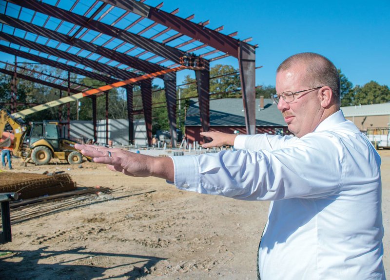 Malvern School District Athletic Director Joe Cook spreads out his hands as he describes the plans for the new gym and the surrounding area that is currently under construction on the Malvern High School campus.