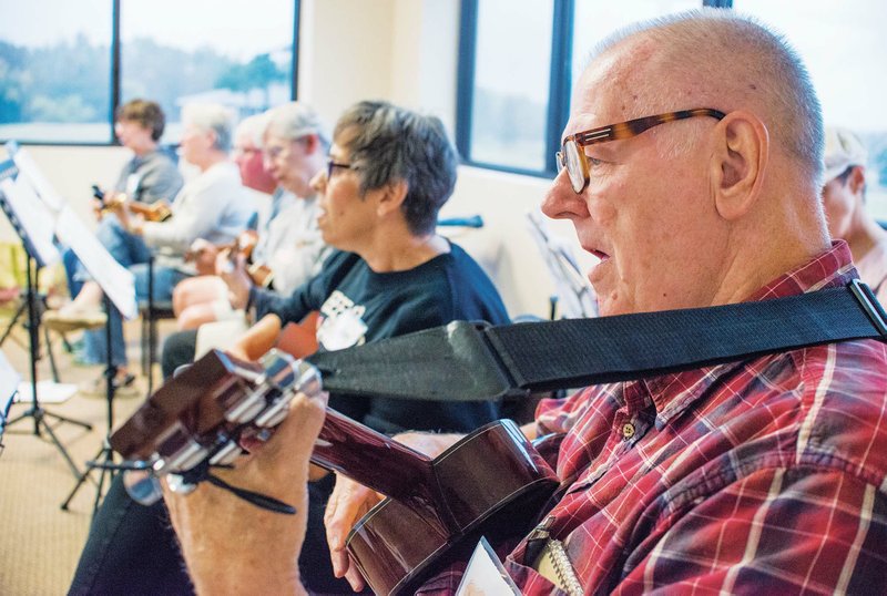 The instrument’s origins can be traced to 19th-century Hawaii. Right: Guy Veazey plays his ukulele along with fellow members of the Hot Springs Ukulele Club in Hot Springs Village while singing “Silent Night.”
