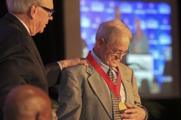 Billy Moore (right) accepts his medal from Southwest Conference Hall of Fame president Carroll Dawson Monday during the 2014 Southwest Conference Hall of Fame induction ceremony in Little Rock.