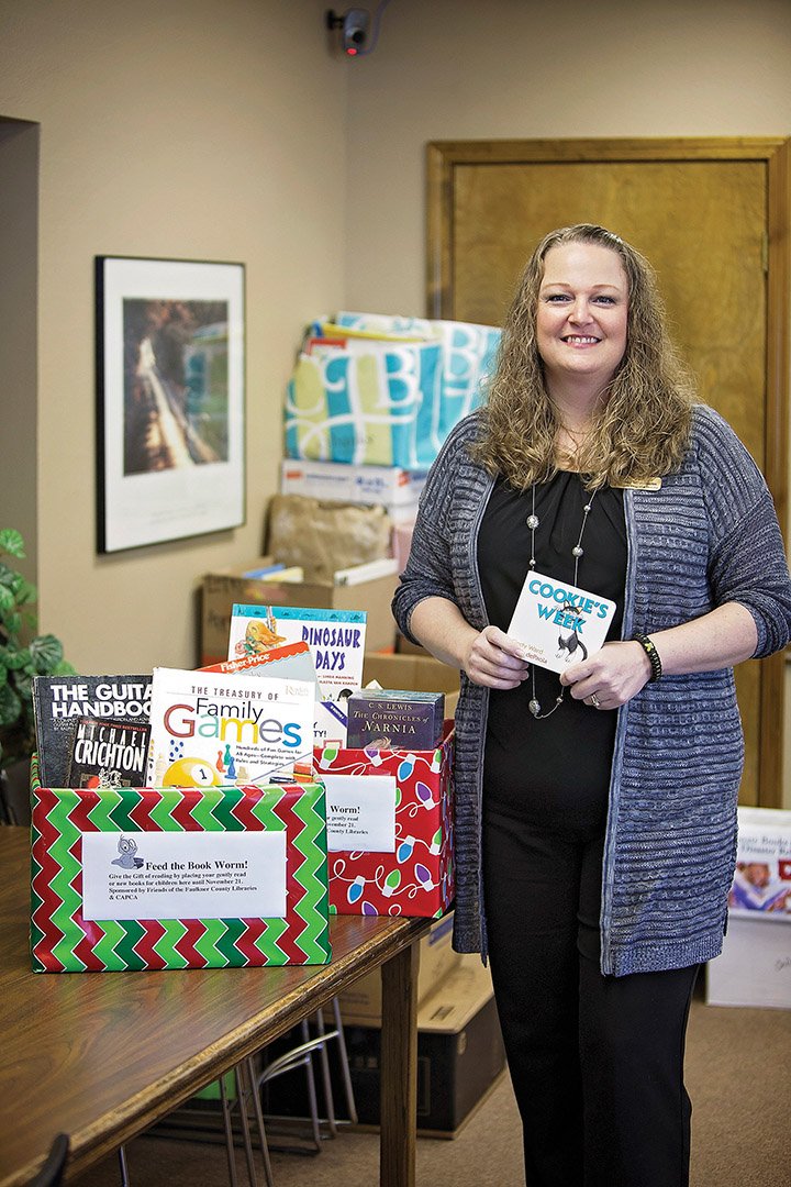 Melissa McWilliams, community program director for Community Action Program for Central Arkansas, stands with books collected for the Bookworm Project, part of the agency’s annual holiday food-box distribution. McWilliams said books are being collected at Faulkner County schools and library branches. Additional food is needed, too, to meet the needs of Faulkner and Cleburne counties.