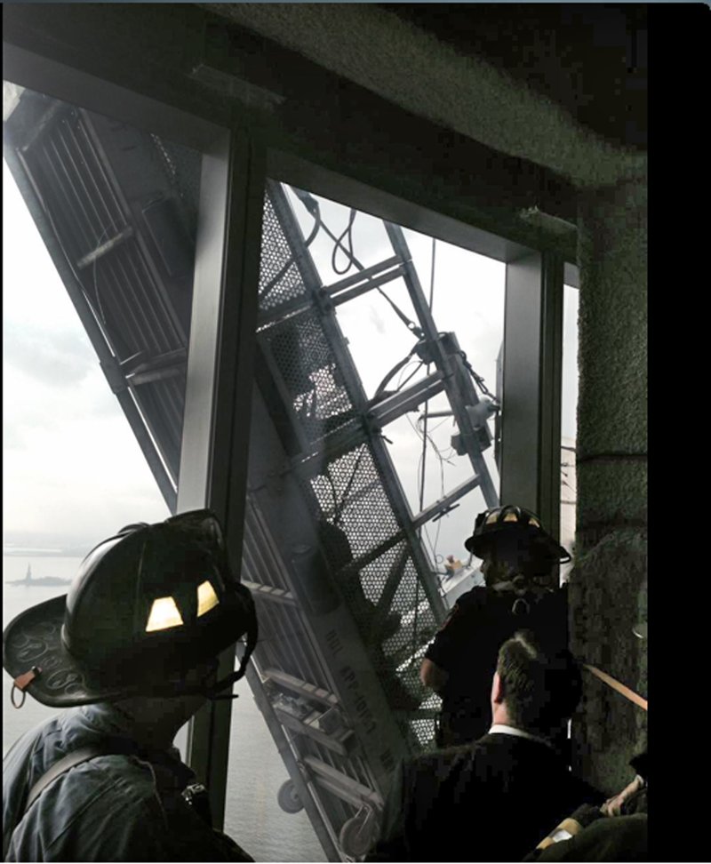 This photo, from the Fire Dept. of New York Twitter page, shows a window washer's gondola as it hangs from 1 World Trade Center, in New York, Wednesday, Nov. 12, 2014. Two workers are stuck on scaffolding 69 stories above street level. A police official, John Miller, says the partially collapsed scaffolding is hanging at "a 75-degree angle." The Fire Department said the workers are tethered and communicating with rescuers.