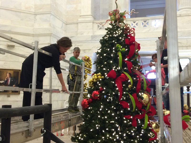 Leighanne Harvey with the state Capitol gift shop and Carla Minchew with Bella Flora Florist work on the 25-foot faux Rockefeller Pine Christmas tree in the state Capitol on Wednesday afternoon. 
