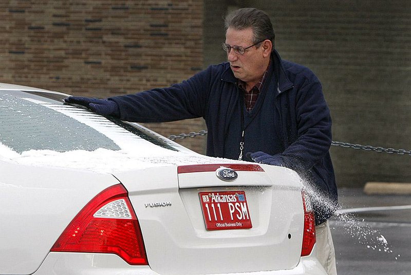 State employee Robert Boyce sweeps the snow off his car Thursday morning in downtown Little Rock. The dusting caught residents and meteorologists off guard ahead of a forecast for snow for the weekend.