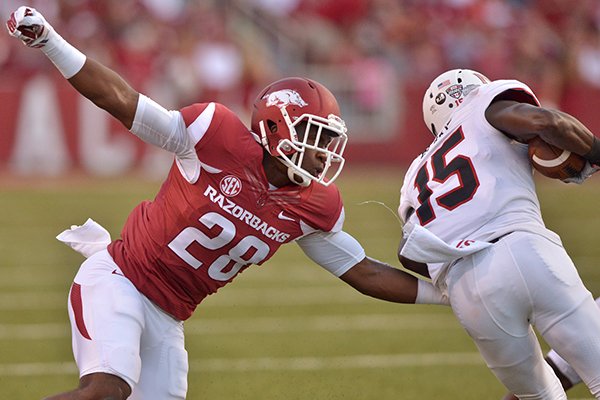 Arkansas defender Josh Liddell attempts to tackle Northern Illinois wide receiver Christian Blake during the second quarter of the game against Northern Illinois in Reynolds Razorback Stadium in Fayetteville on Saturday, Sept. 20, 2014.