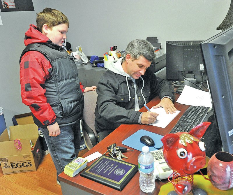 Staff Photo Michael Woods &#8226; @NWAMICHAELW Nicholas, 10, watches as his dad, Will Thompson, sketches out a basic drawing of how their float for the Springdale Christmas parade will look like on Sunday morning at the BTX kids office in Springdale.