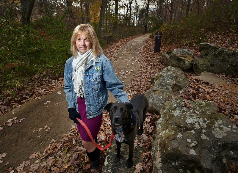 Mary Ley, CEO of the Arkansas Arts Academy, poses for a photo with her dog Chloe near the North gate of the Crystal Bridges Museum of American Art trail system, just a short walk from her home in Bentonville, on Friday Nov. 14, 2014. 