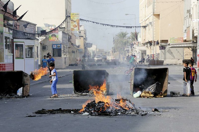 Bahraini children play by burning debris left on a street where clashes occurred between police and anti-government protesters on a parliamentary election day in the Shiite village of Malkiya, Bahrain, Saturday, Nov. 22, 2014. Voters in Bahrain cast ballots Saturday in the island kingdom's first full parliamentary election since Arab Spring-inspired protests erupted four years ago, but a boycott called by the country's opposition threatens to overshadow the poll. (AP Photo/Hasan Jamali)