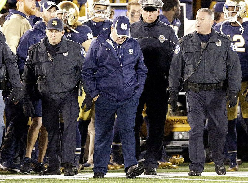 Notre Dame head coach Brian Kelly, center, looks down as he walks on the field after Notre Dame's 31-28 loss to Louisville in an NCAA college football game in South Bend, Ind., Saturday, Nov. 22, 2014. (AP Photo/Nam Y. Huh)