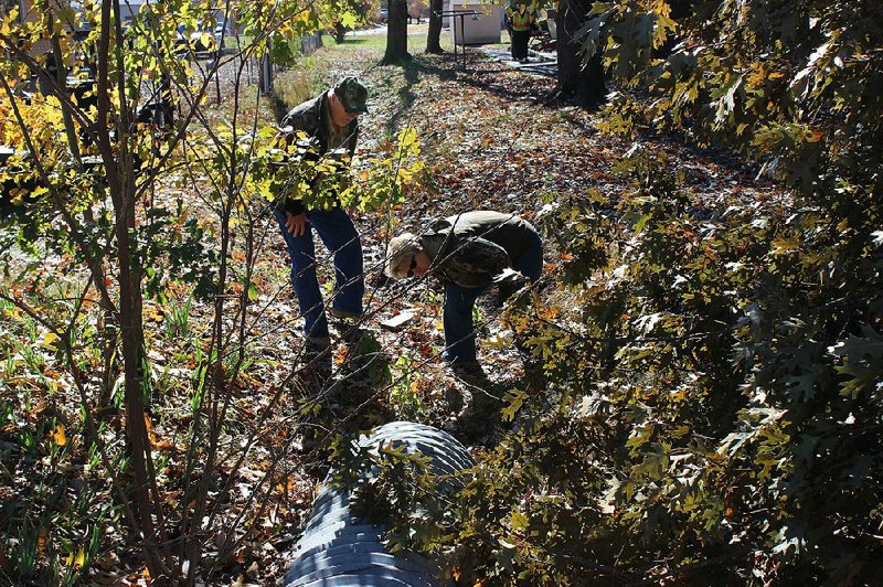 Arkansas Online/GAVIN LESNICK - Martin Ghent and his wife, Linda Ghent, look in a drainage pipe west of where 2-year-old Malik Drummond went missing while searching the area Monday morning. "We saw it on the news and thought it was the right thing to do," Martin Ghent said of joining the search efforts.