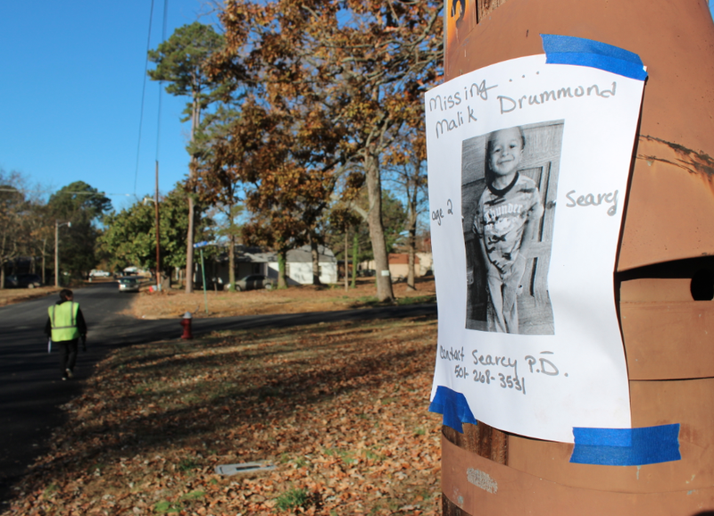 Volunteer searcher Pat Munson walks Park Avenue in Searcy looking for missing toddler Malik Drummond beside a missing poster taped to a utility pole on Nov. 25, 2014.