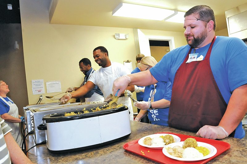 STAFF PHOTO FLIP PUTTHOFF Walmart employees Jeff Fleming, from left, Markise Hammonds, Lisa Adams and Ryan Wolfe dish up traditional Thanksgiving dinners Tuesday at Samaritan Community Center in Rogers.