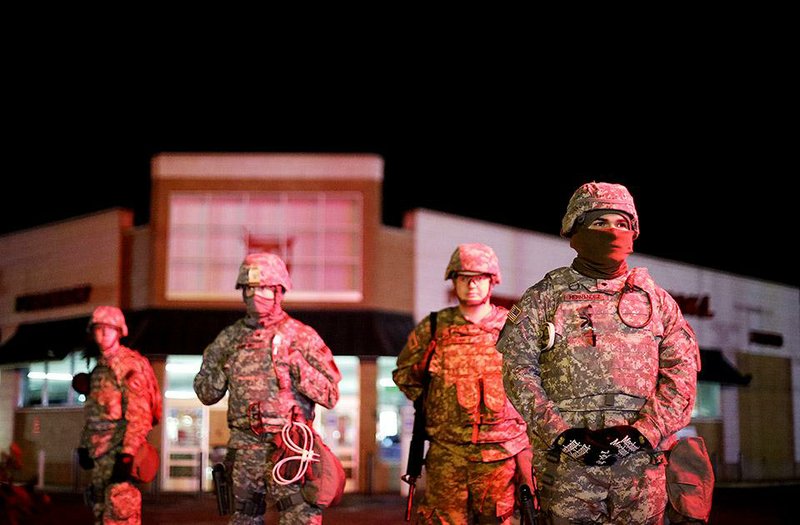 Missouri National Guard troops stand watch Wednesday morning outside a Walgreens store in Ferguson. In one commercial area of the city, a soldier was stationed in front of every few stores, and some were on rooftops.